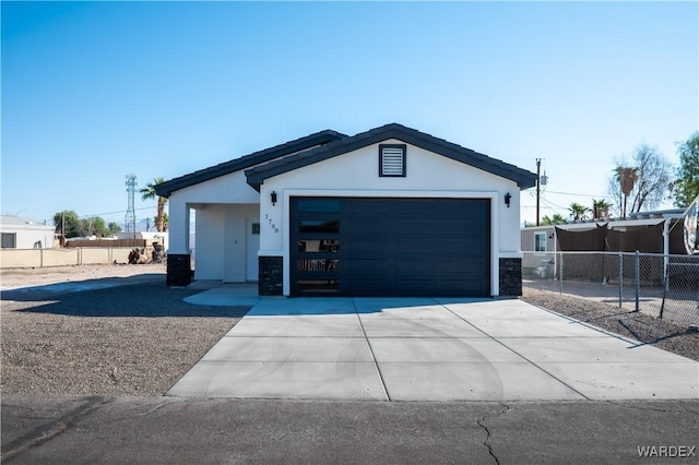 view of front of home with concrete driveway, an attached garage, fence, and stucco siding