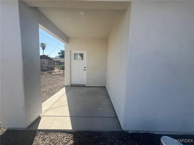 view of exterior entry featuring a patio area and stucco siding