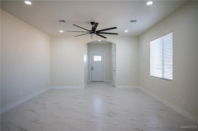 empty room with baseboards, visible vents, arched walkways, marble finish floor, and recessed lighting