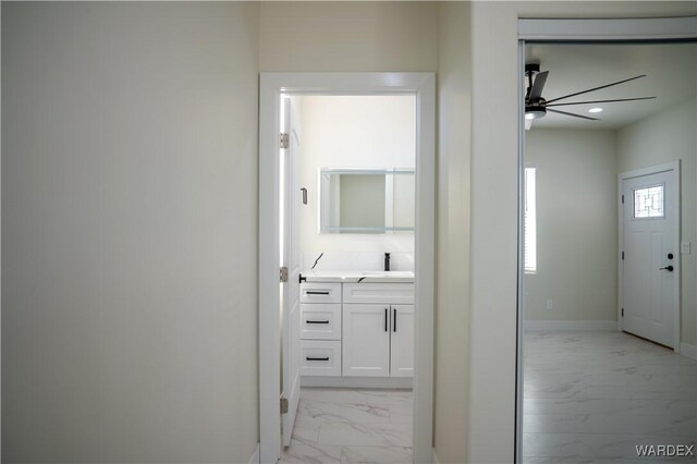 corridor with marble finish floor, recessed lighting, a sink, and baseboards