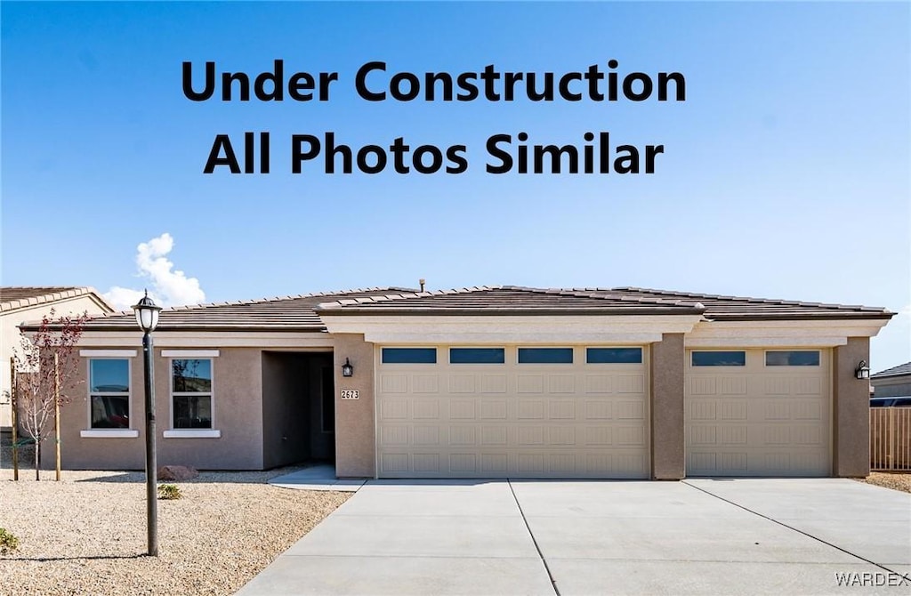 view of front of property with a garage, concrete driveway, a tiled roof, and stucco siding