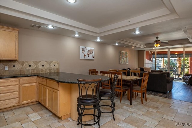 kitchen featuring tasteful backsplash, a raised ceiling, a ceiling fan, open floor plan, and a peninsula