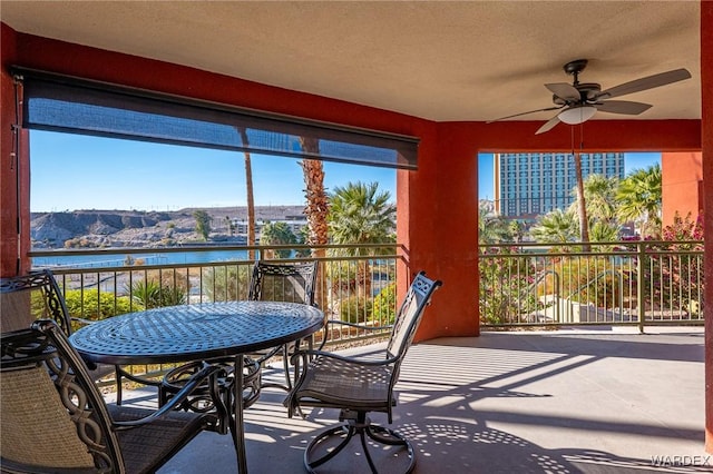 sunroom with ceiling fan and a water and mountain view