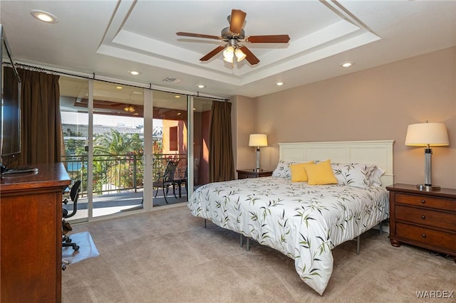 bedroom featuring access to exterior, a raised ceiling, light carpet, and floor to ceiling windows