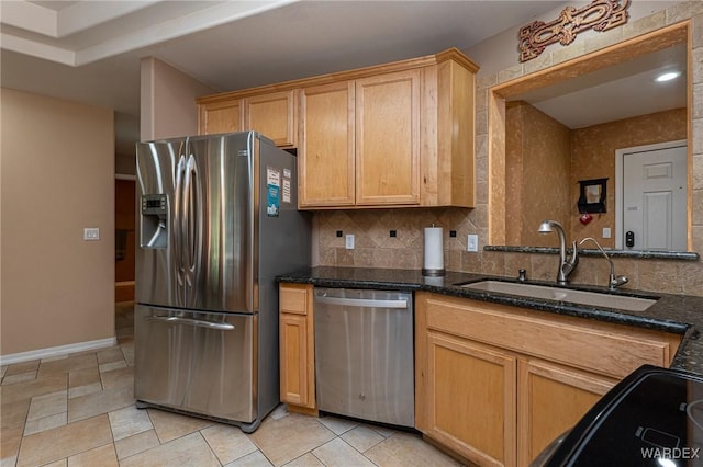 kitchen with dark stone counters, appliances with stainless steel finishes, a sink, and decorative backsplash