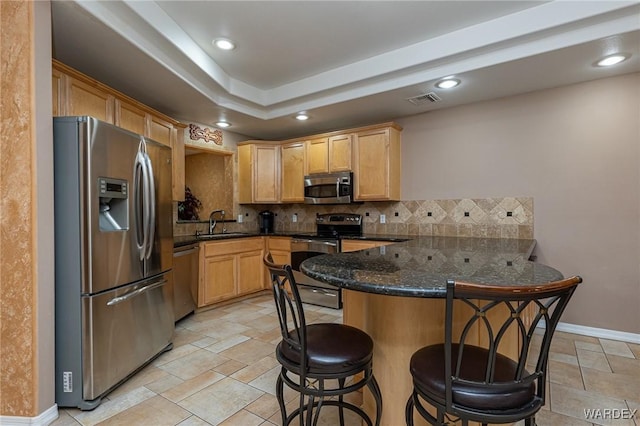 kitchen with decorative backsplash, appliances with stainless steel finishes, a kitchen breakfast bar, a peninsula, and a sink