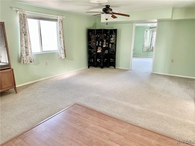 empty room with light colored carpet, ceiling fan, and baseboards