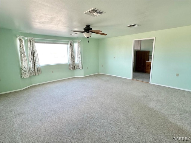 spare room with light colored carpet, visible vents, ceiling fan, and baseboards