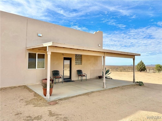 rear view of property featuring a patio and stucco siding