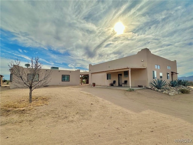 rear view of house with a patio and stucco siding