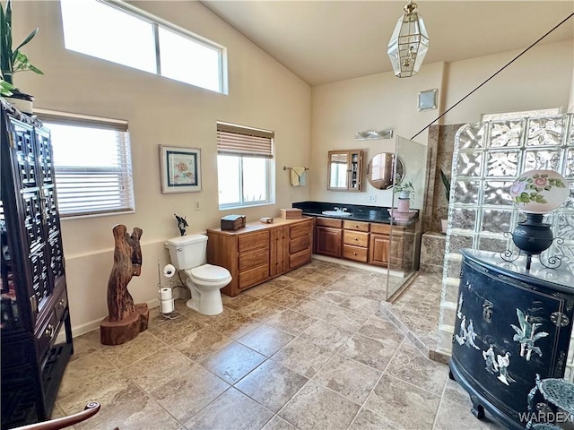 full bath featuring baseboards, toilet, a high ceiling, walk in shower, and vanity