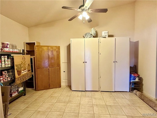 interior space with ceiling fan, vaulted ceiling, and light tile patterned floors