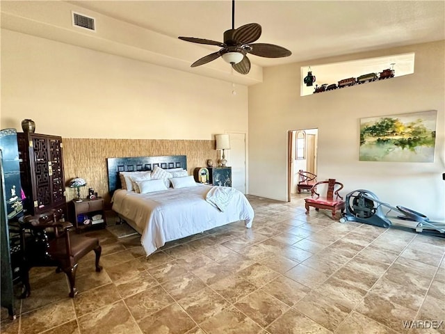 bedroom with visible vents, ceiling fan, and a towering ceiling