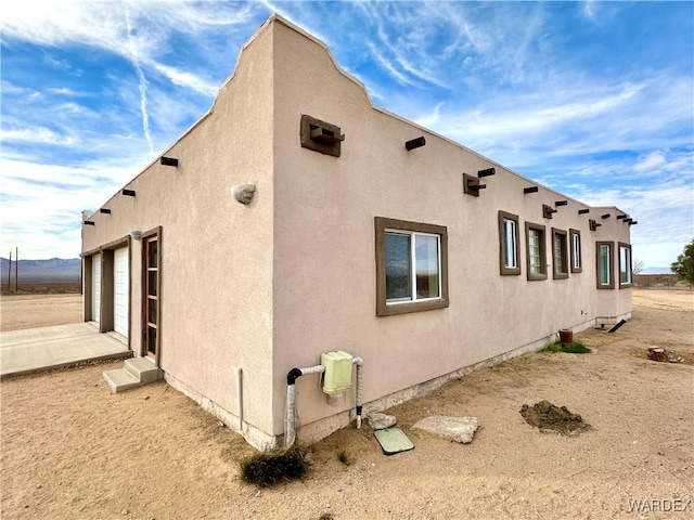 view of side of property with a garage and stucco siding