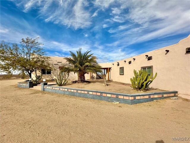 rear view of house featuring stucco siding