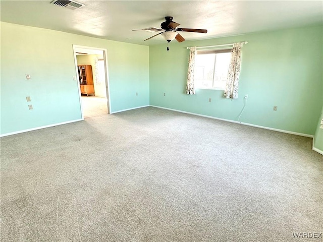 spare room with ceiling fan, carpet floors, visible vents, and baseboards