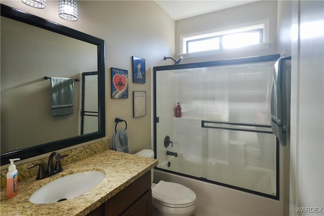 bathroom with shower / bath combination with glass door, vanity, and toilet