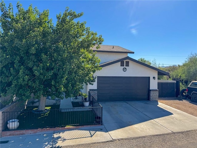 1189 Juanita Ln, Bullhead City, AZ 86442 - view of front of property featuring driveway, a fenced front yard, stucco siding, a gate, and an attached garage