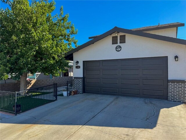 1189 Juanita Ln, Bullhead City, AZ 86442 - view of front of home featuring stucco siding, concrete driveway, an attached garage, and brick siding