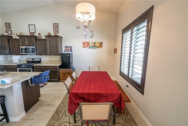 dining space featuring plenty of natural light, lofted ceiling, baseboards, and light tile patterned floors