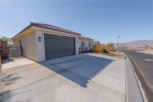 garage featuring concrete driveway, a mountain view, and a gate