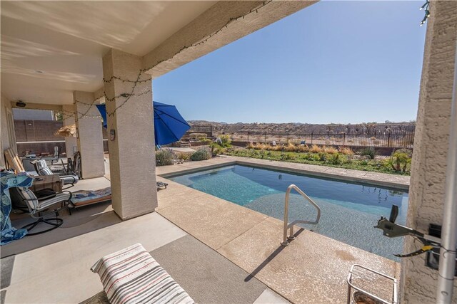 swimming pool featuring a patio, fence, and a mountain view