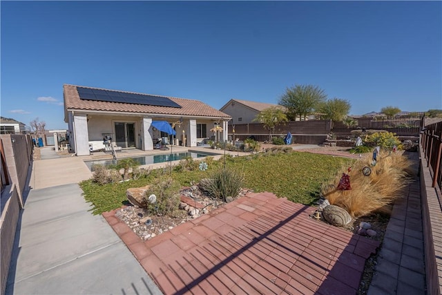 rear view of house with solar panels, a patio, a fenced backyard, a tiled roof, and stucco siding