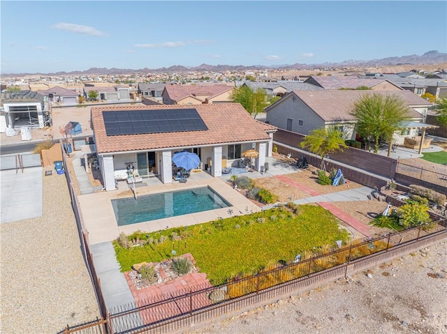 back of house featuring a fenced backyard, a residential view, solar panels, and a patio