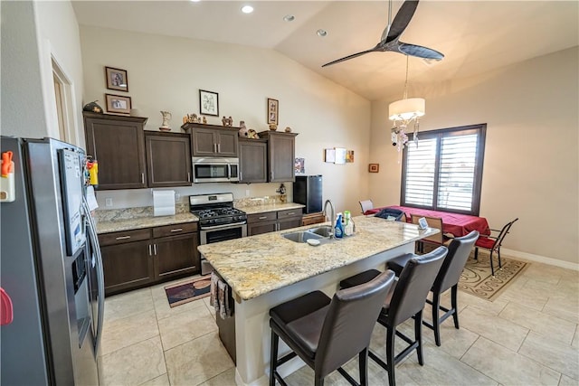 kitchen featuring stainless steel appliances, a sink, vaulted ceiling, dark brown cabinets, and a breakfast bar