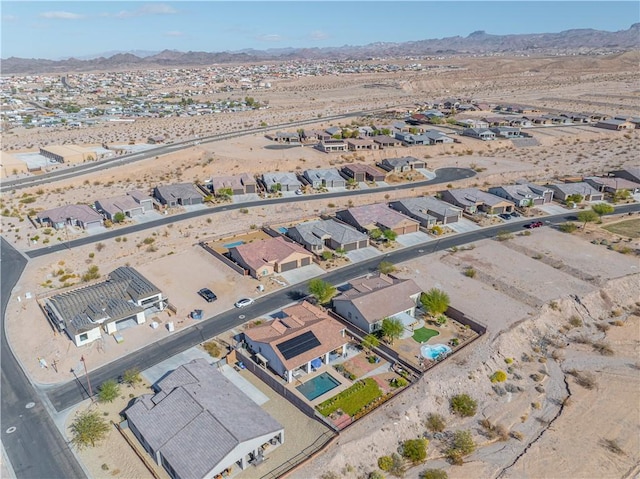 aerial view of residential area featuring a mountainous background and a desert landscape