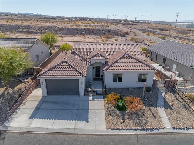 mediterranean / spanish-style home with a garage, a tiled roof, stucco siding, fence, and driveway
