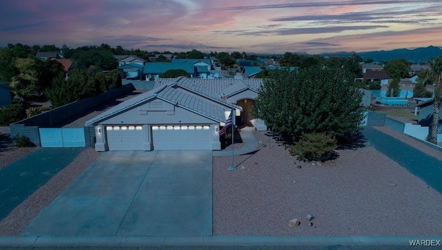 exterior space featuring driveway, a garage, a tile roof, a residential view, and fence