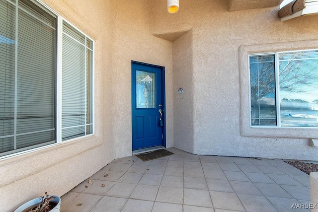 view of exterior entry with a patio area and stucco siding