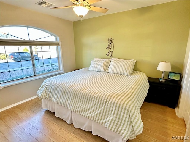 bedroom featuring light wood-type flooring, baseboards, visible vents, and ceiling fan