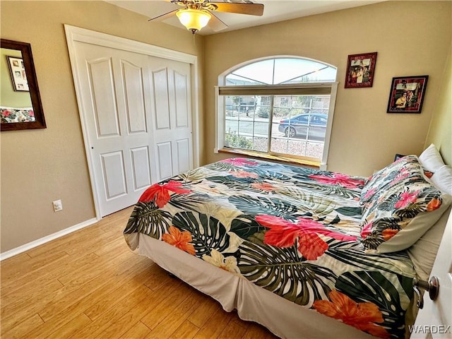 bedroom with light wood-style floors, a ceiling fan, baseboards, and a closet