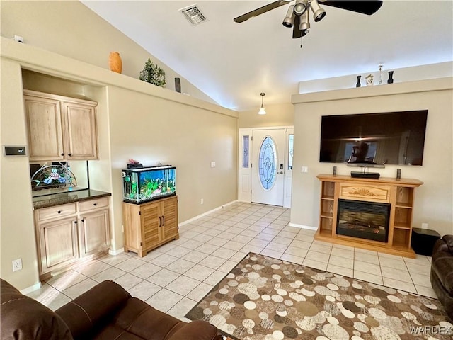 entryway with lofted ceiling, visible vents, a ceiling fan, a glass covered fireplace, and light tile patterned flooring