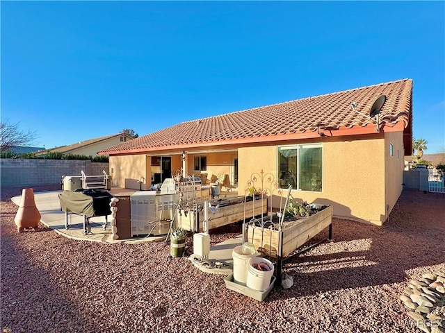 rear view of property with a patio, a tile roof, fence, and stucco siding