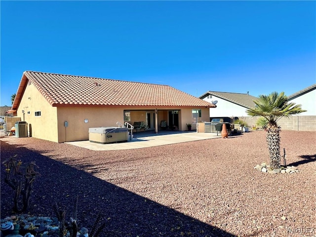 rear view of property with a fenced backyard, cooling unit, a tile roof, stucco siding, and a hot tub