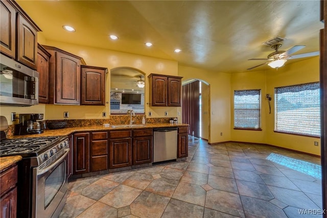 kitchen with arched walkways, stainless steel appliances, a sink, visible vents, and a ceiling fan