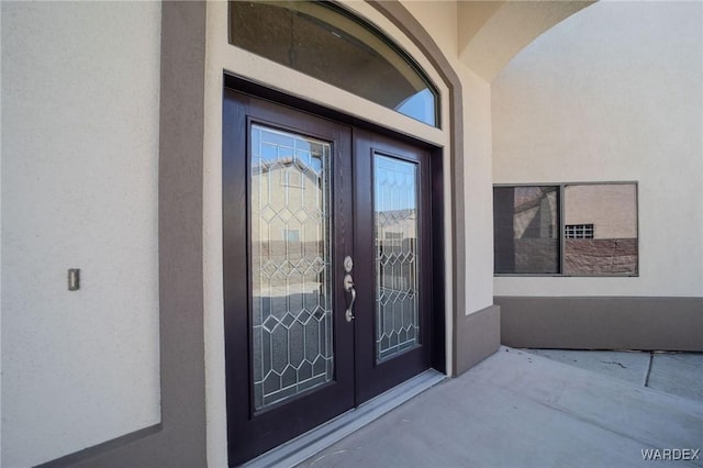 property entrance featuring stucco siding and french doors