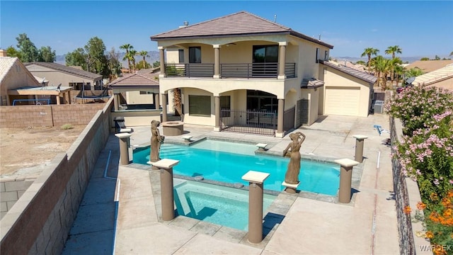 back of property with stucco siding, a pool with connected hot tub, a patio, a fenced backyard, and a balcony