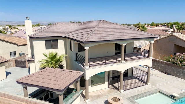 rear view of house with a tile roof, stucco siding, a gazebo, a patio area, and a balcony