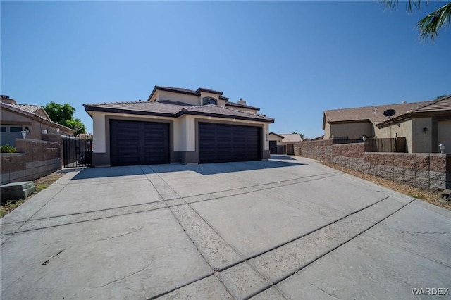 exterior space with driveway, a tiled roof, an attached garage, fence, and stucco siding