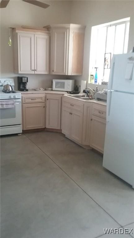 kitchen featuring white appliances, concrete floors, light countertops, and a sink