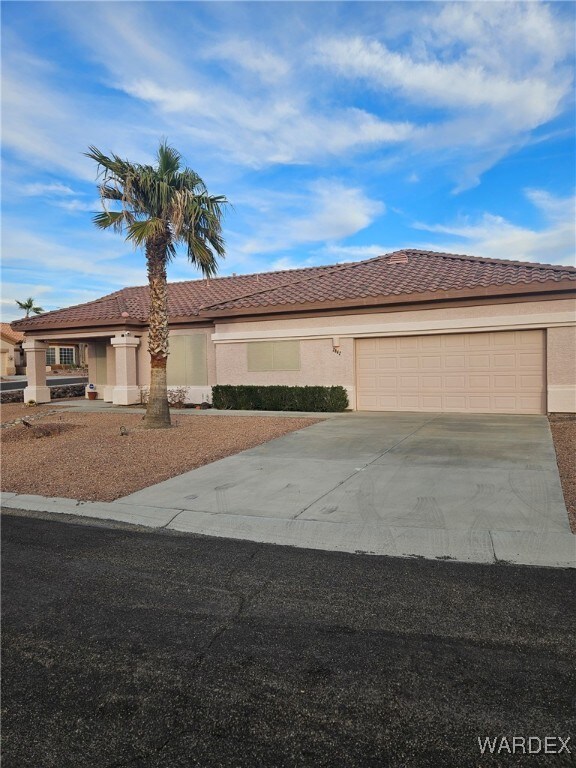 view of front of home with driveway, an attached garage, a tile roof, and stucco siding