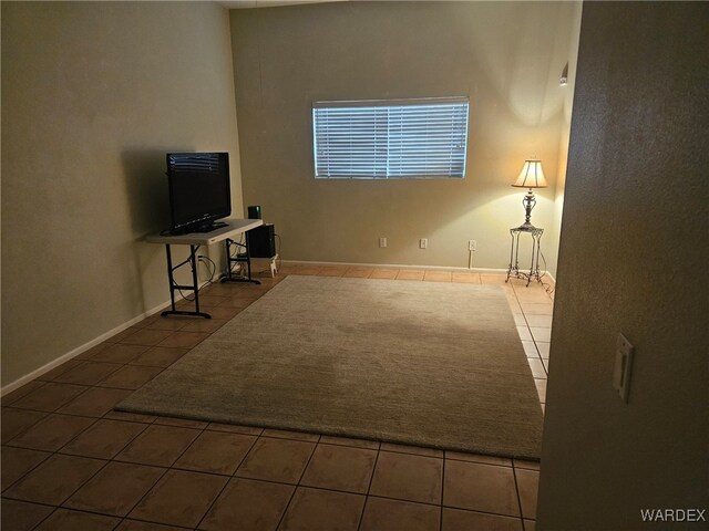 unfurnished living room featuring dark tile patterned flooring and baseboards