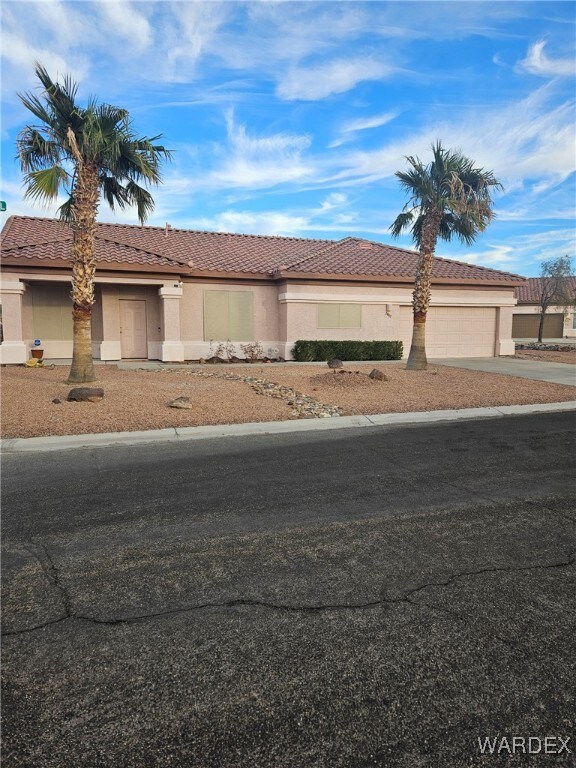 townhome / multi-family property with a tiled roof, an attached garage, driveway, and stucco siding