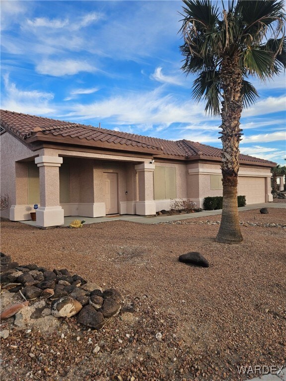 view of front facade with a tiled roof, an attached garage, and stucco siding