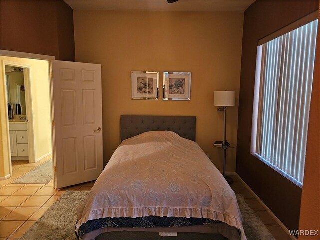 bedroom featuring light tile patterned flooring, a sink, and baseboards