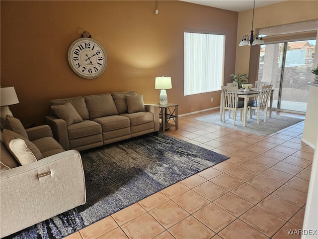 tiled living room featuring a chandelier and baseboards